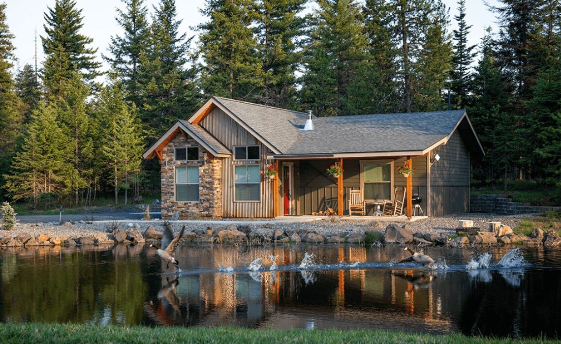 cabin on a lake with pine trees in the background