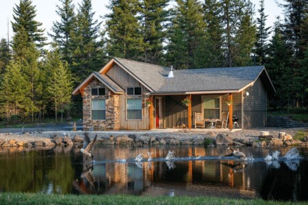cabin on a lake with pine trees in the background